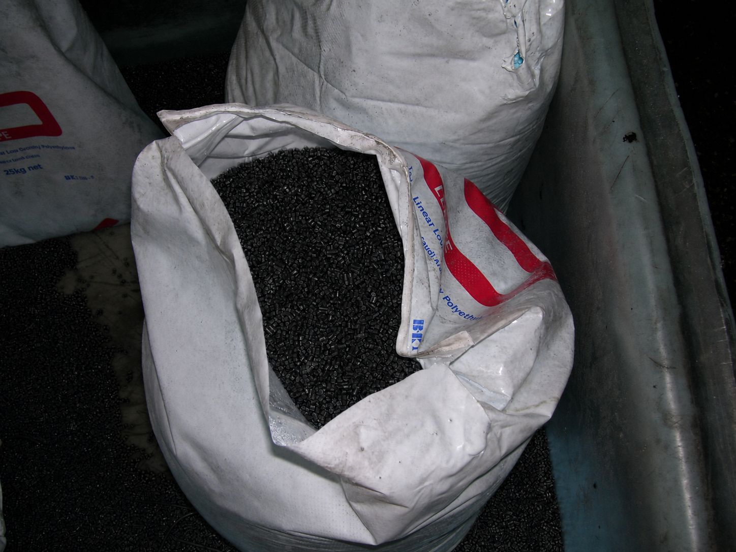 Production photograph of black masterbatch pellets in an open industrial bag